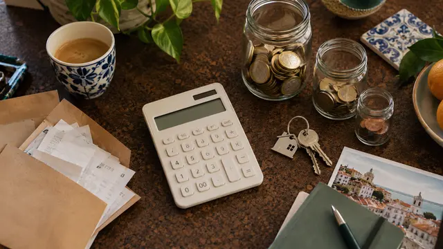 Top-down photograph of a relocation budget workspace: a cream calculator.