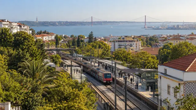 Greater Lisbon-inspired suburban rail corridor with a leafy station.