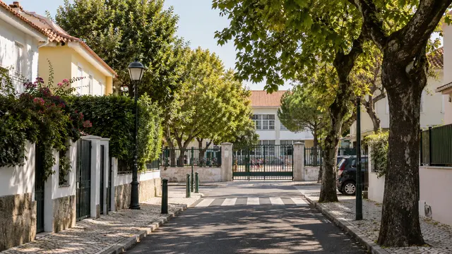 A quiet walkable residential lane ending at a school gate.