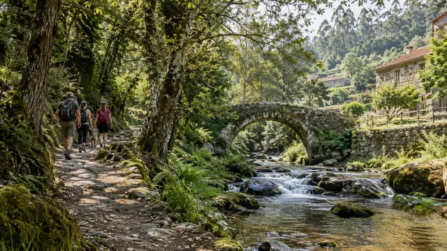 A small group walking a Portuguese woodland trail beside a stream.