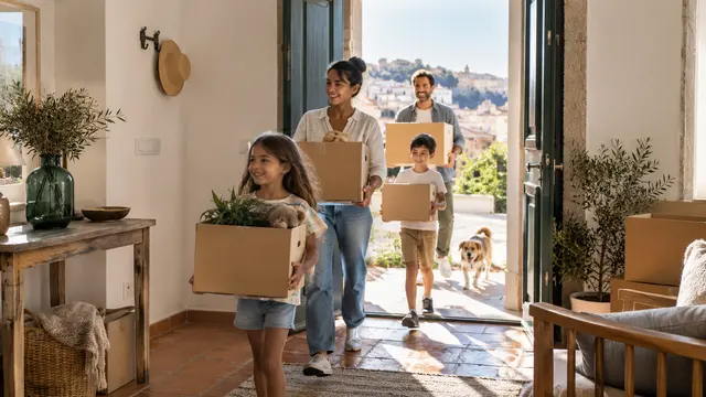 A family carrying the last light moving boxes across a Portuguese home's open threshold.